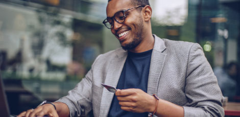 A man who is smiling and holding a credit card.