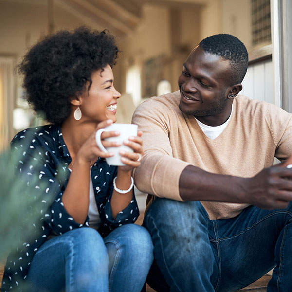 Couple smiling at each other and holding mugs