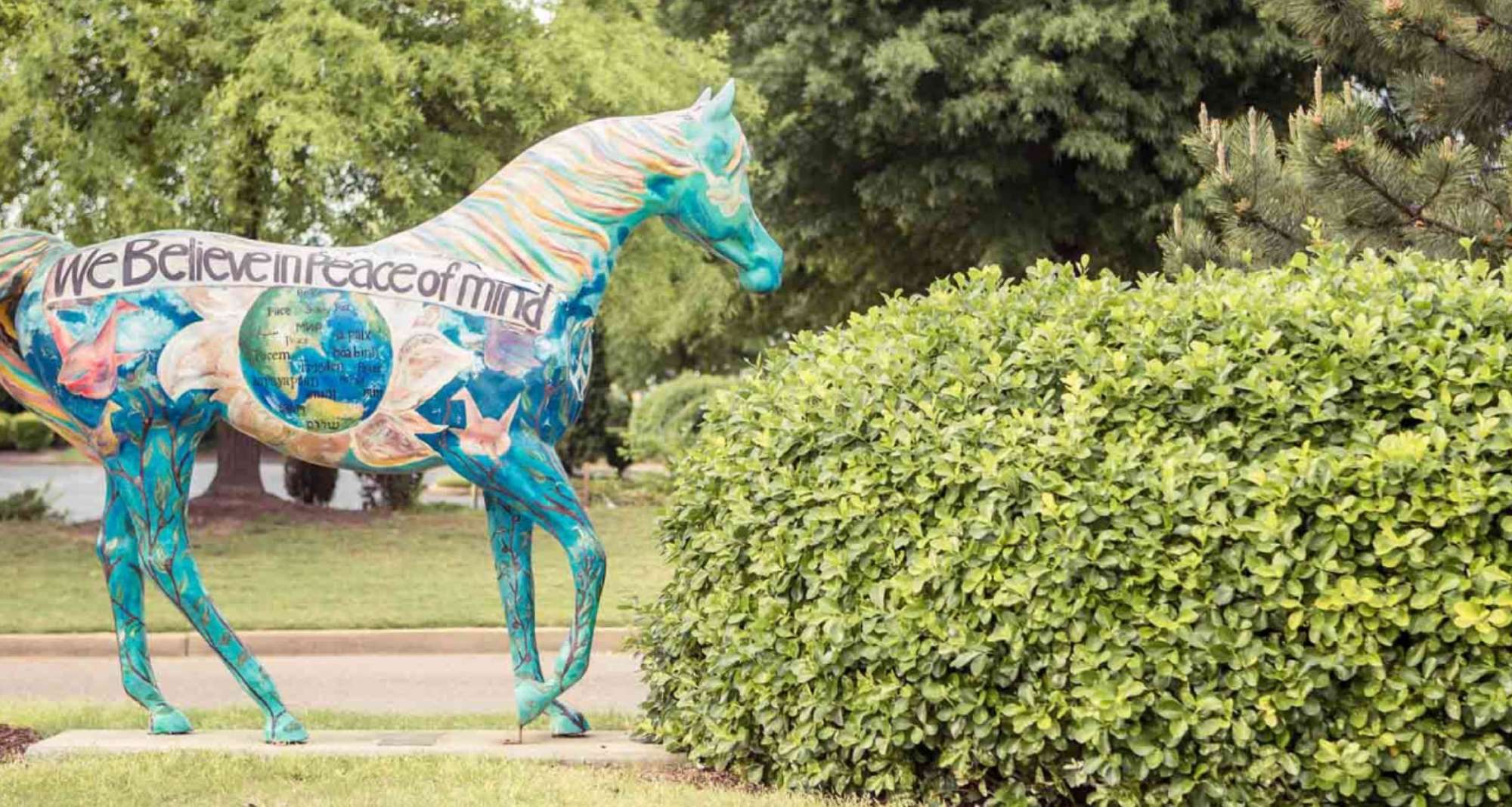 A picture of a horse sculpture. The horse is colorful and has words on it that say, "We believe in peace of mind."