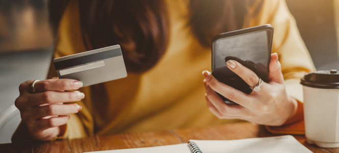 Close up of a person's hands, one is holding a credit card while the other is holding a smart phone