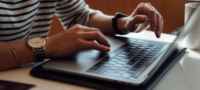 Close up of someone's hands over the keyboard of a laptop.