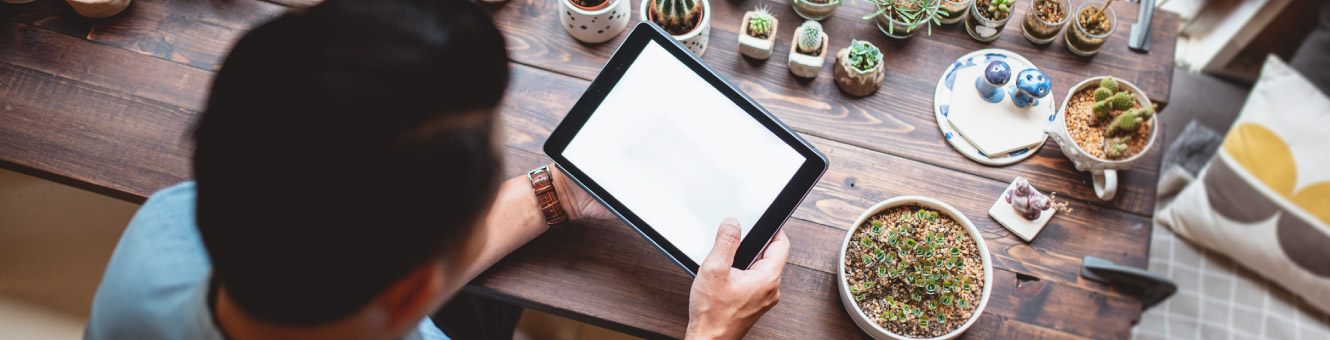 Looking over-the-shoulder of a man holding a tablet.