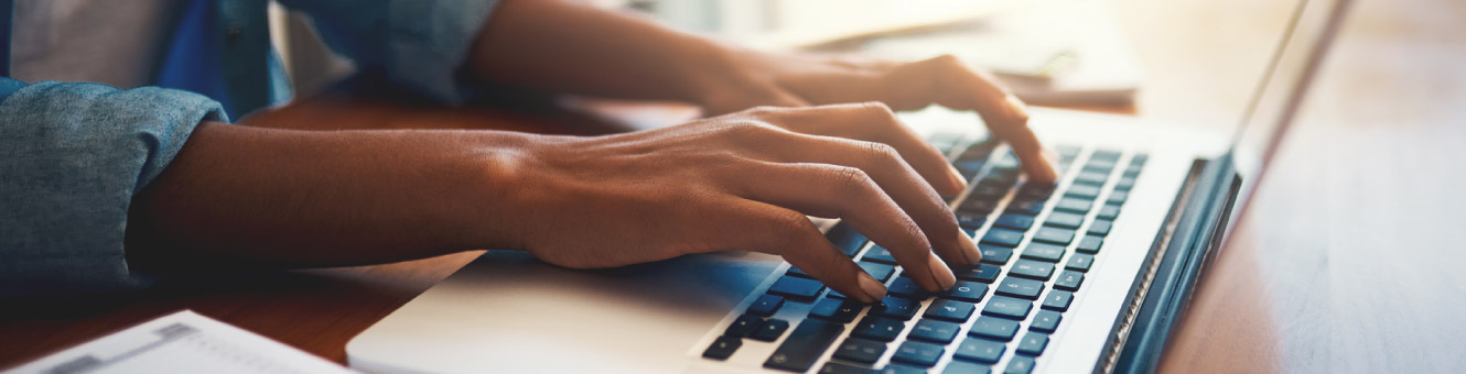 Close up of a person's hands typing on a laptop keyboard